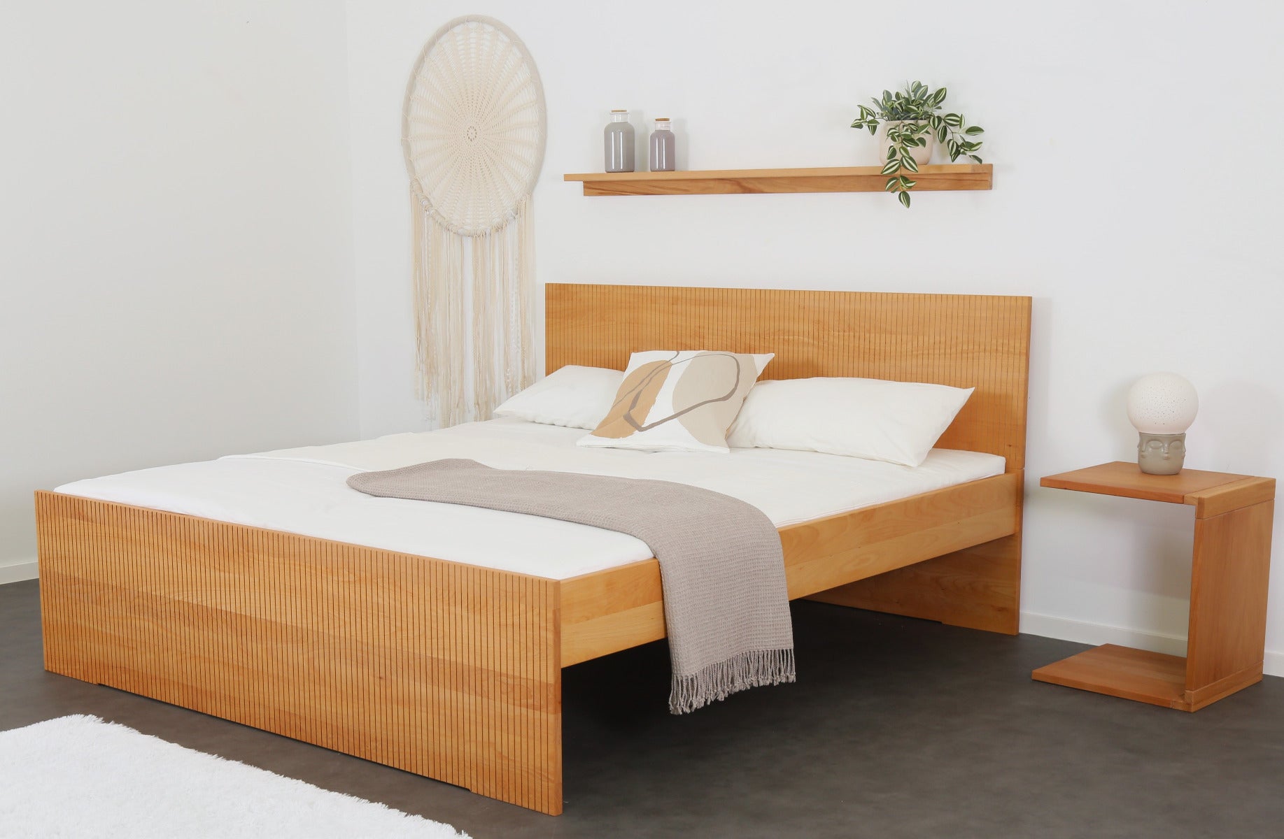 Schräge Frontalansicht von Bett Aikana in Buche mit Rückwand und Front mit gefrästem Streifen-Design