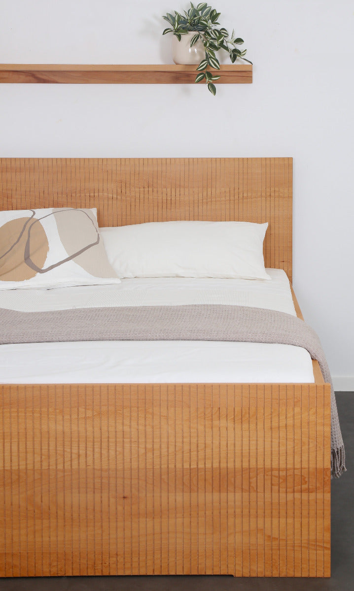 Frontalansicht von Bett Aikana in Buche mit Rückwand und Front mit gefrästem Streifen-Design