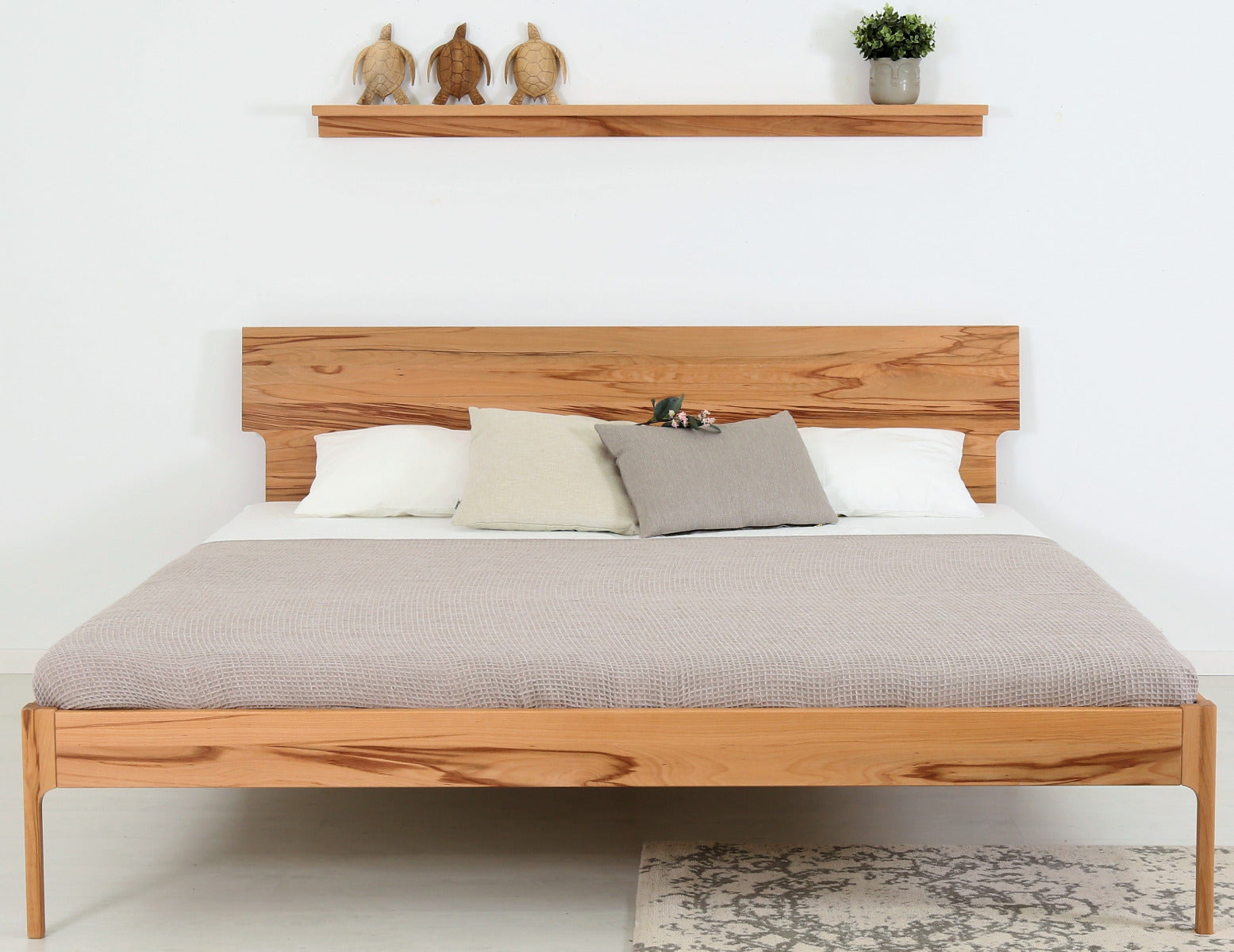Frontalansicht von Bett Noa Tai in Kernbuche mit filigranen Holzfüßen und Designerlehne