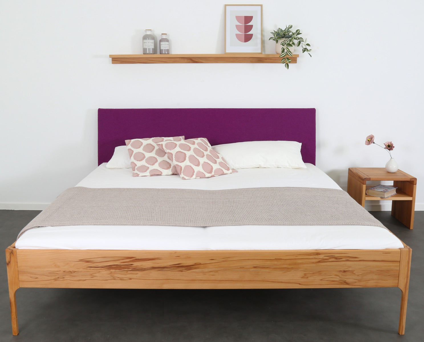 Frontalansicht von Bett Ona S in Kernbuche mit filigranen Füßen und rechteckiger Stofflehne in beere