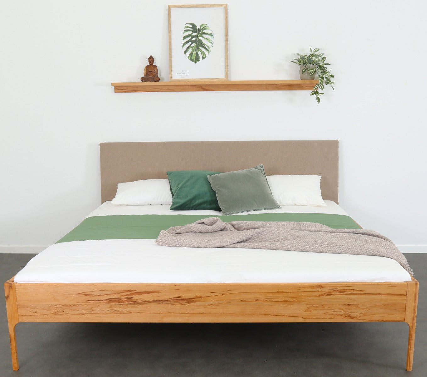 Frontalansicht von Bett Ona S in Kernbuche mit filigranen Füßen und rechteckiger Stofflehne in beige