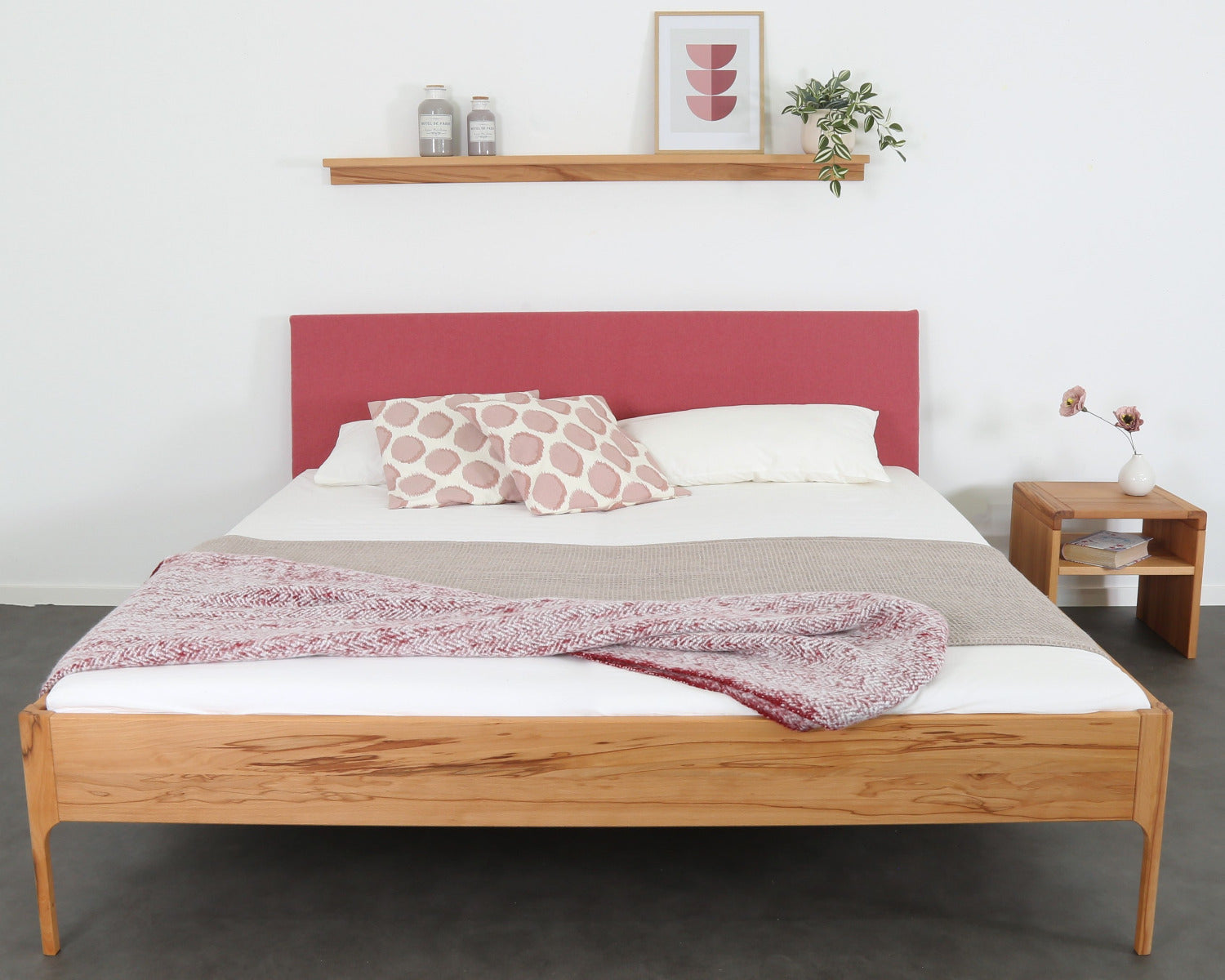 Frontalansicht von Bett Ona S in Kernbuche mit filigranen Füßen und rechteckiger Stofflehne in flamingo