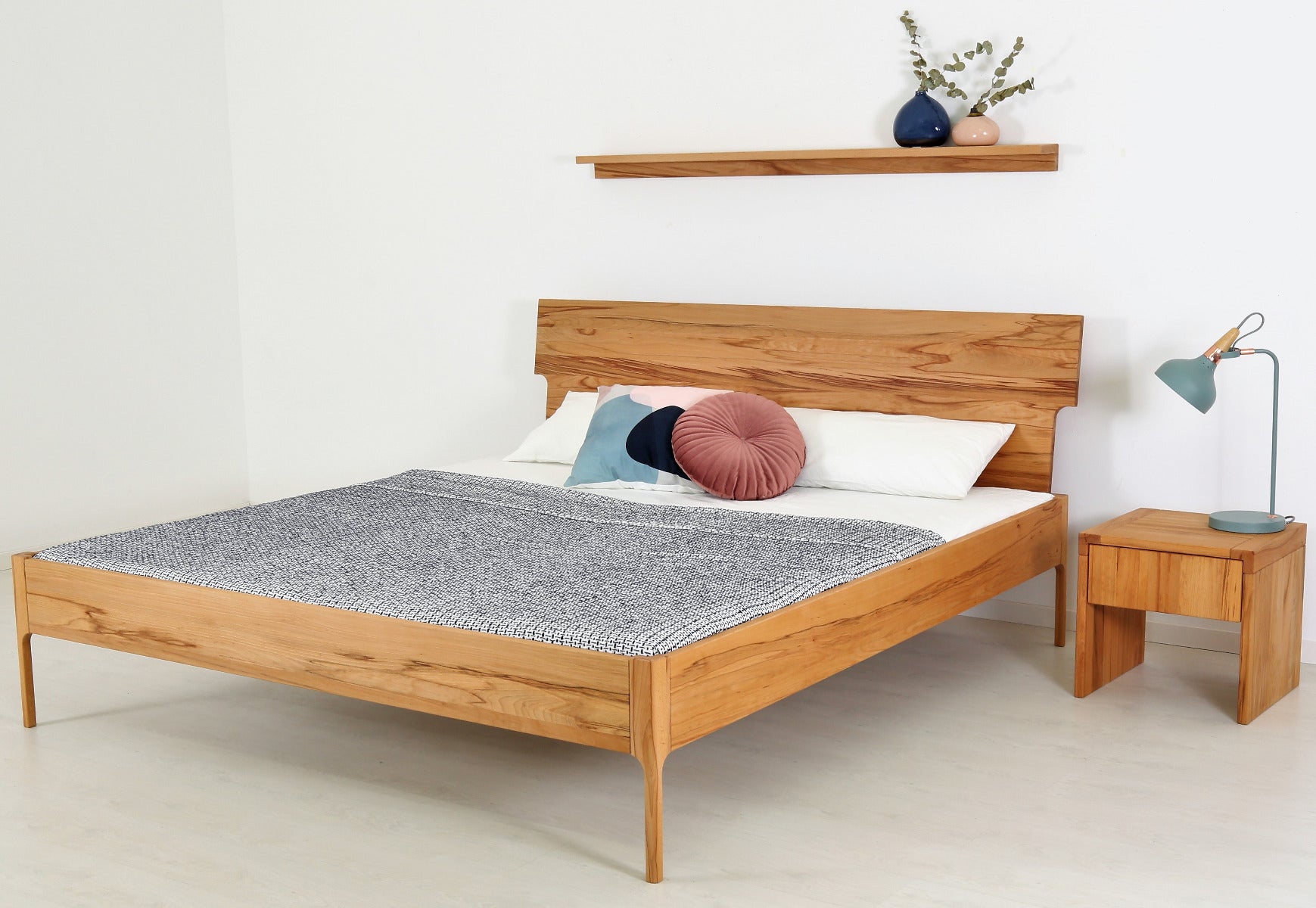 Schräge Frontalansicht von Bett Noa Tai in Kernbuche mit filigranen Holzfüßen und Designerlehne
