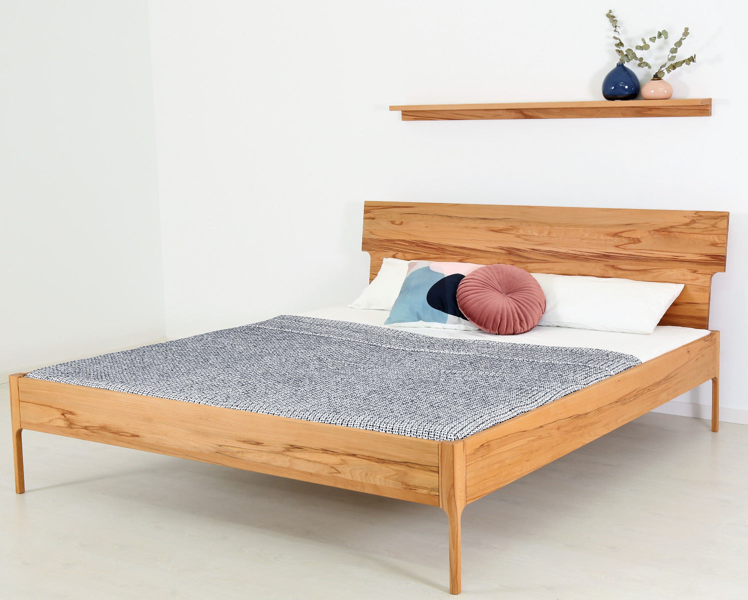 Schräge Frontalansicht von Bett Noa Tai in Kernbuche mit filigranen Holzfüßen und Designerlehne