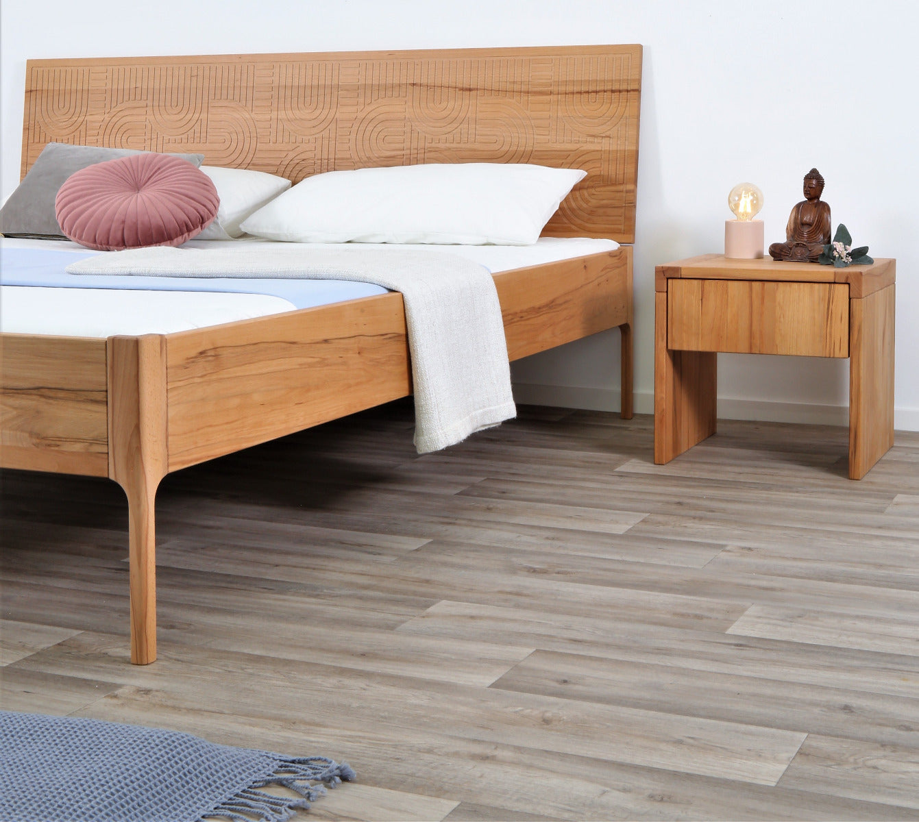 Schräge Frontalansicht von Bett Ona Zen in Kernbuche mit filigran gefräster Lehne und filigranen Füßen