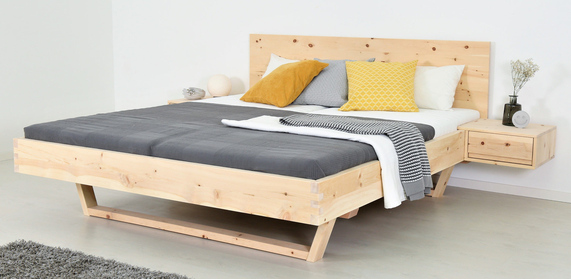 Schräge Frontalansicht von Bett Xeta in Zirbe mit Holzkufen und schlichter rechteckiger Lehne