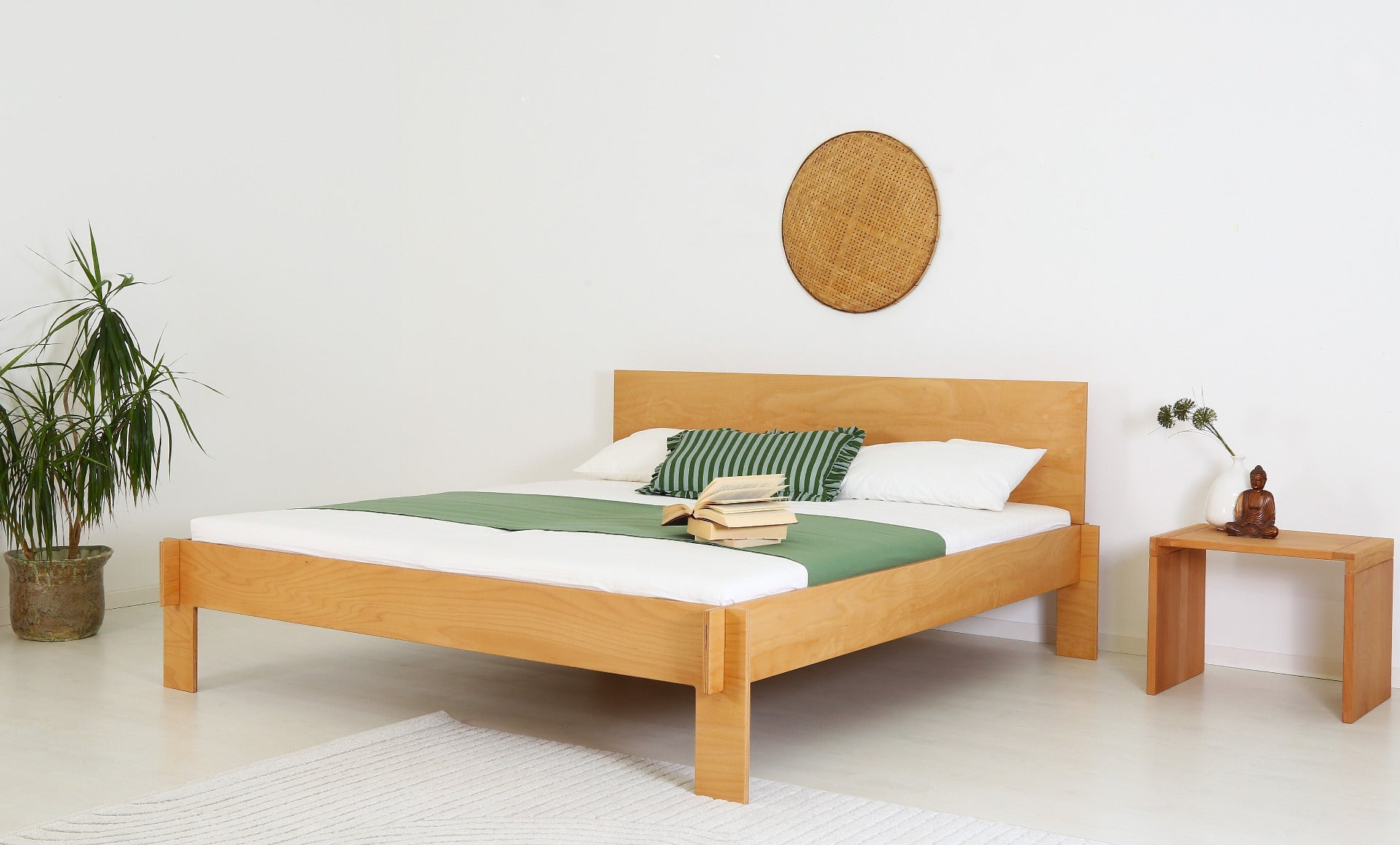 Schräge Frontansicht des Bettes Mul in Buche-Multiplex mit der schlichten Lehne und dem simplen gesteckten Aufbau.