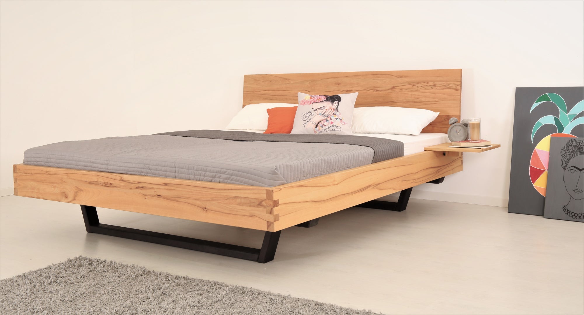 Schräge Frontalansicht von Bett Cofan in Kernbuche mit Kufe aus schwarz gebeizter/geölter Buche und schlichter, rechteckiger Lehne