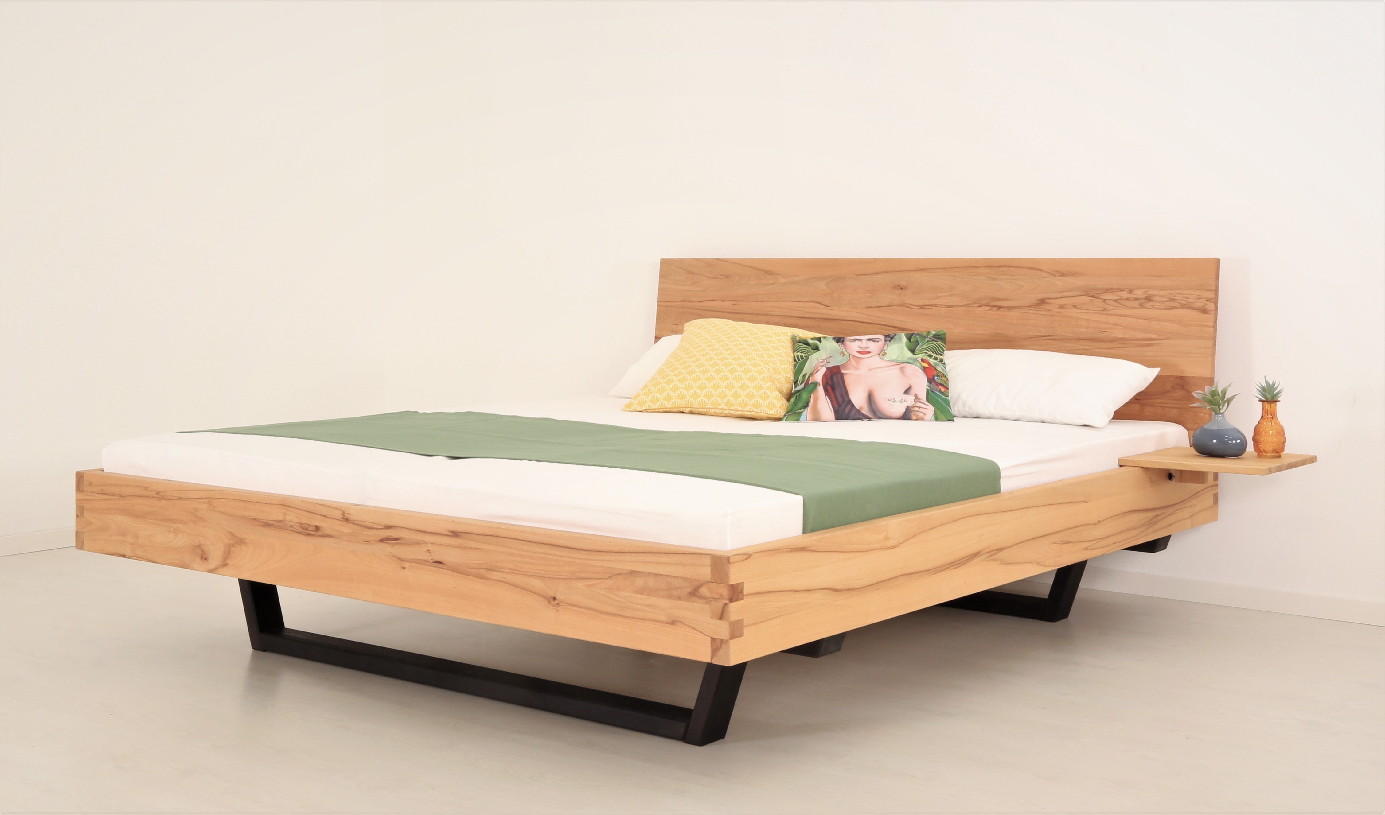 Schräge Frontalansicht von Bett Cofan in Kernbuche mit Kufe aus schwarz gebeizter/geölter Buche und schlichter, rechteckiger Lehne