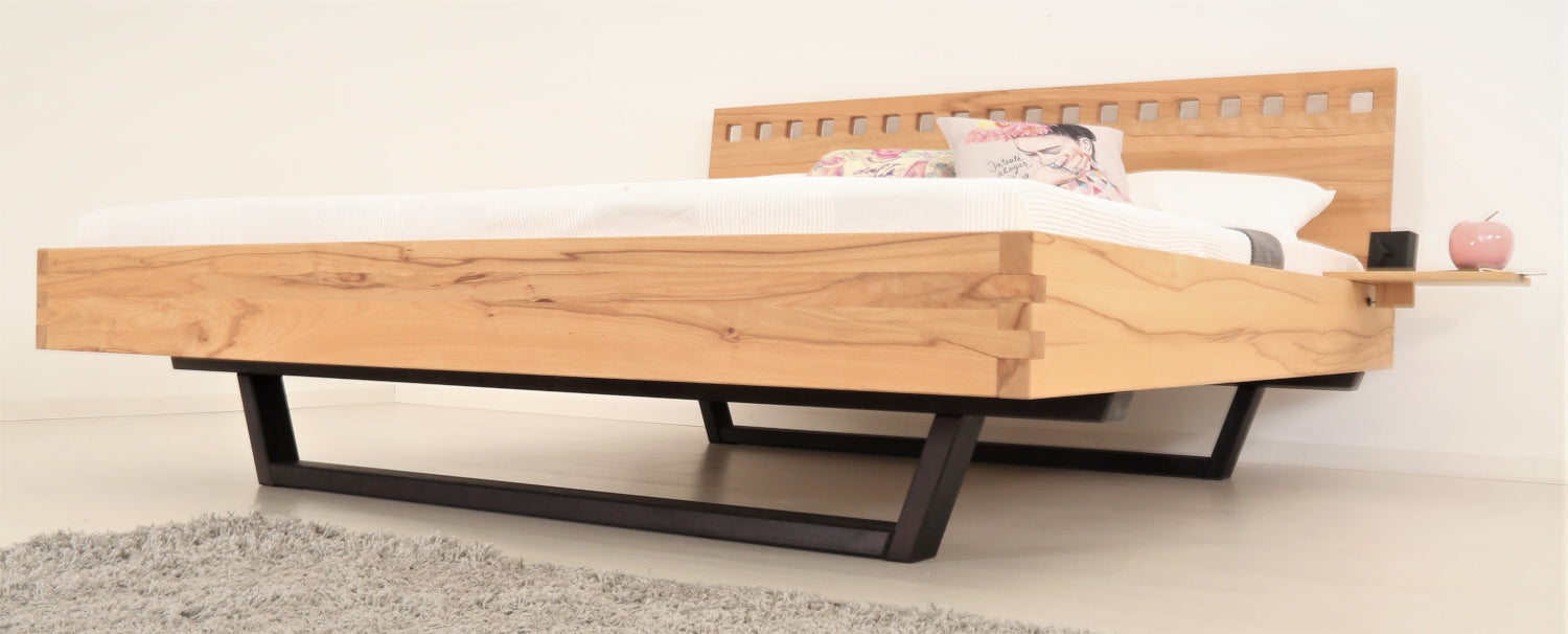 Schräge Frontalansicht von Bett Cofan mit Kufe aus schwarz gebeizter/geölter Buche und Lehne mit quadratischen Durchbrüchen