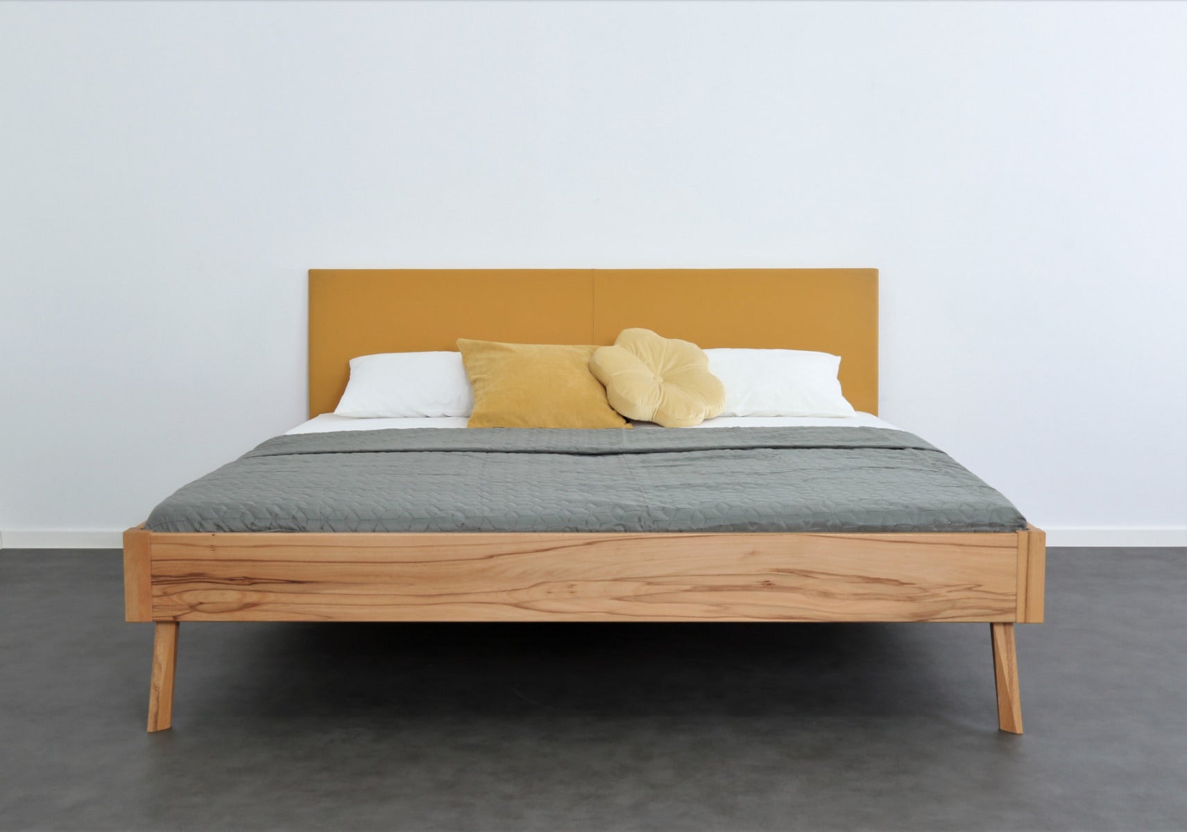 Frontalansicht von Bett Tuxa Premium mit filigranen Füßen und Rinderlederlehne in Kurkuma