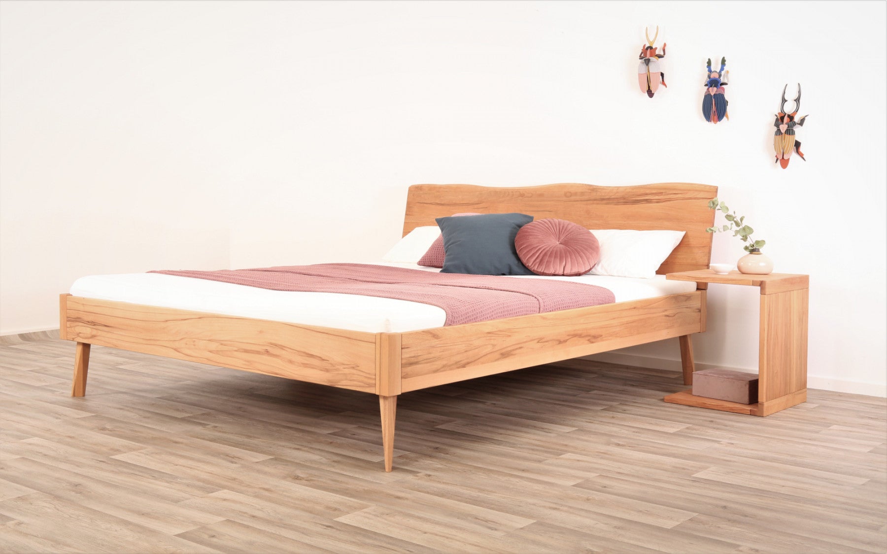 Schräge Frontalansicht von Bett Tuxa Wood in Kernbuche mit filigranen Füßen und Baumkantenlehne