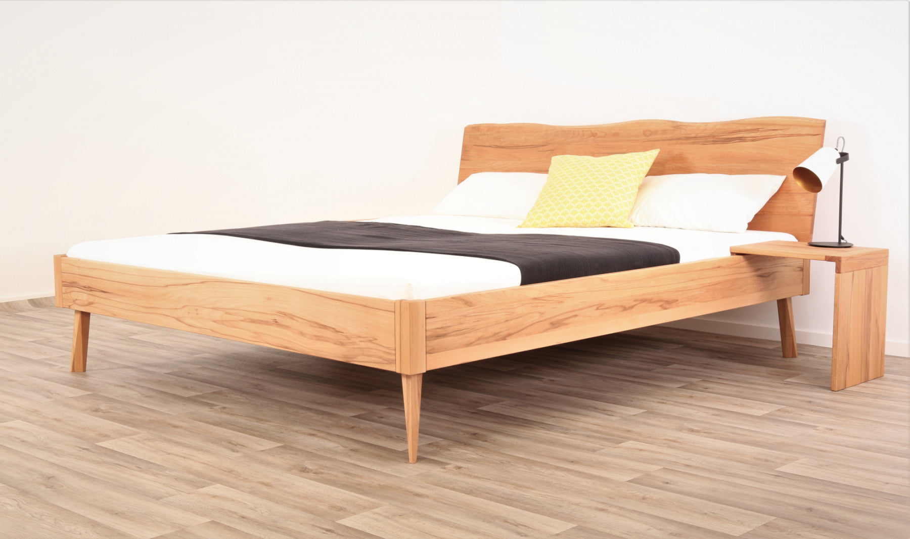 Schräge Frontalansicht von Bett Tuxa Wood in Kernbuche mit filigranen Füßen und Baumkantenlehne