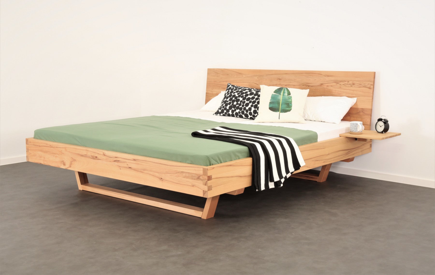 Schräge Frontalansicht von Bett Xeta 01 mit schlichter rechteckiger Rückenlehne und Holzkufen