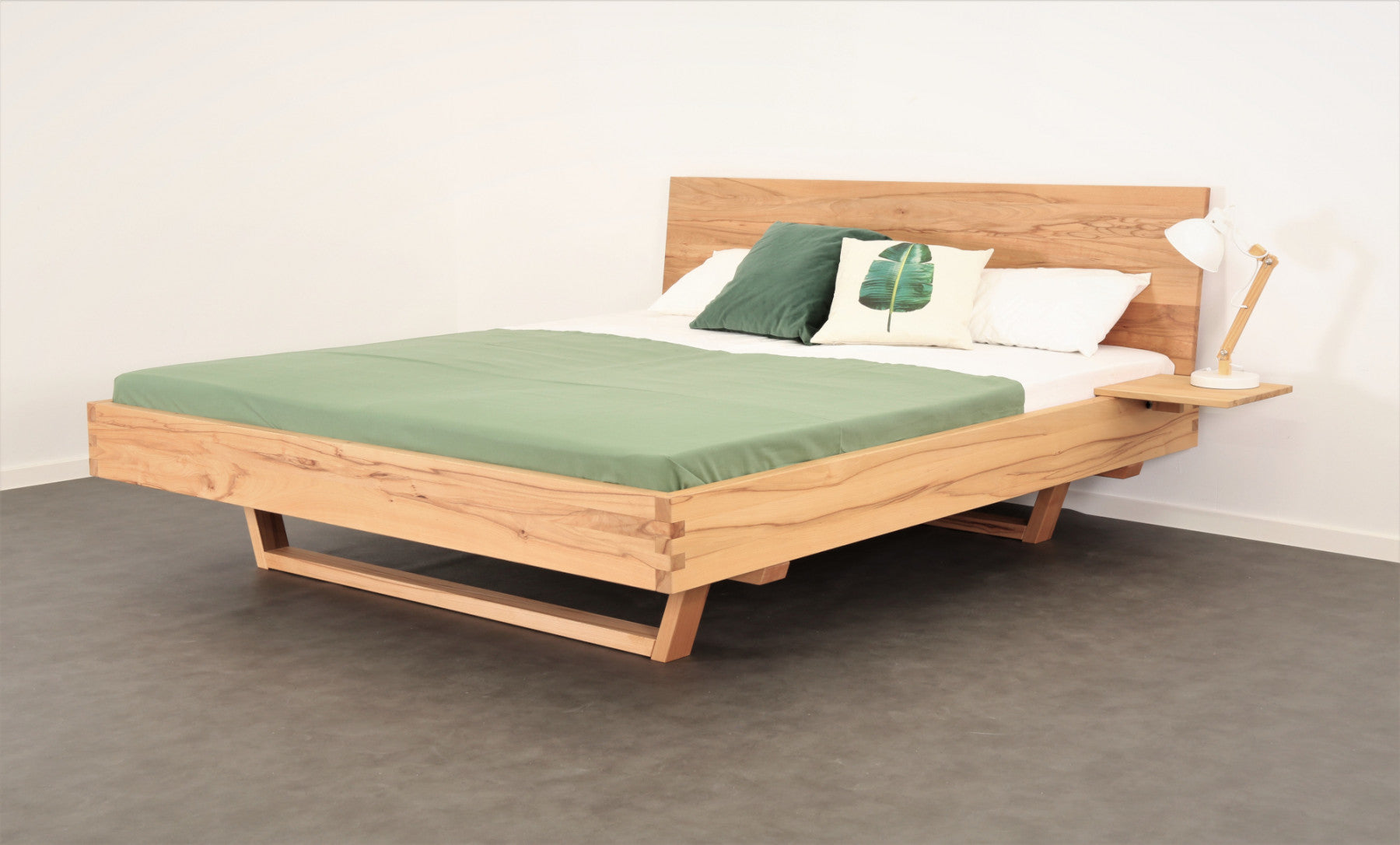 Schräge Frontalansicht von Bett Xeta 01 mit schlichter rechteckiger Rückenlehne und Holzkufen