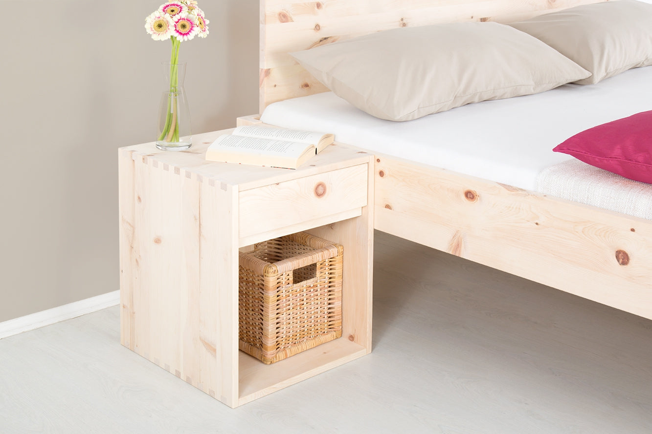 Schräge Frontalansicht von Nachttisch Ainu 1 mit einem Schubfach und einer Ablage, in der ein kleiner geflochtener Korb steht.