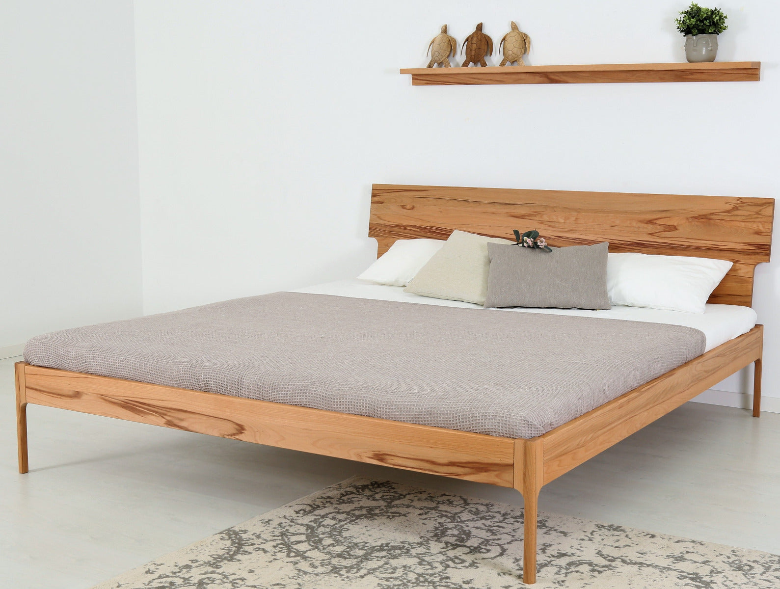 Schräge Frontalansicht von Bett Noa Tai in Kernbuche mit filigranen Holzfüßen und Designerlehne