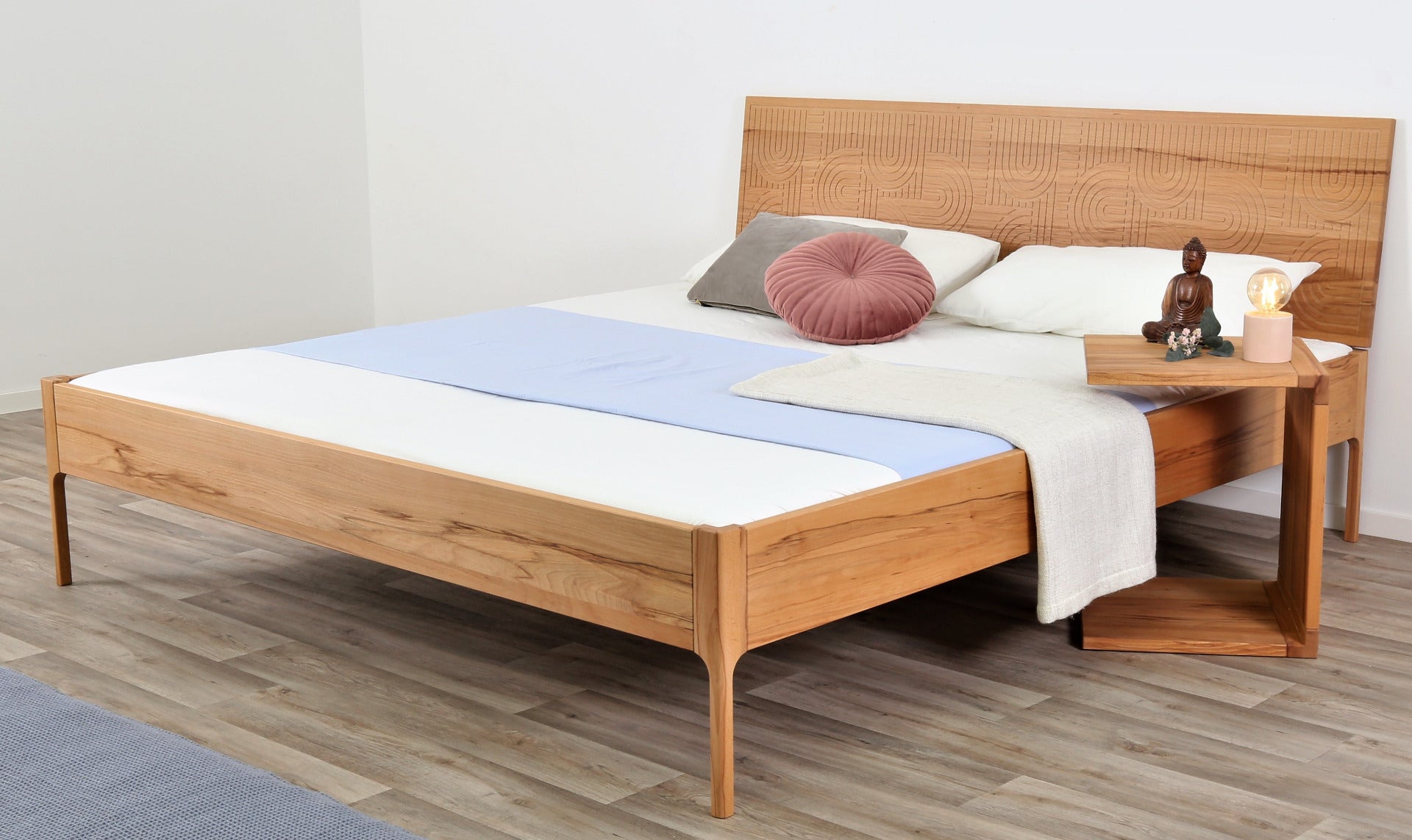 Schräge Frontalansicht von Bett Ona Zen in Kernbuche mit filigran gefräster Lehne und filigranen Füßen
