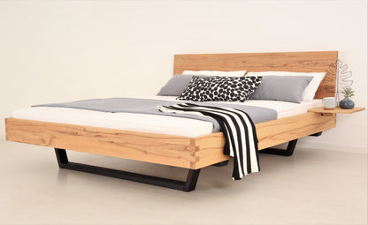 Schräge Frontalansicht von Bett Cofan in Kernbuche mit Kufe aus schwarz gebeizter/geölter Buche und schlichter, rechteckiger Lehne
