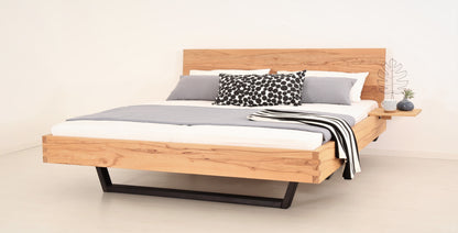 Schräge Frontalansicht von Bett Cofan in Kernbuche mit Kufe aus schwarz gebeizter/geölter Buche und schlichter, rechteckiger Lehne
