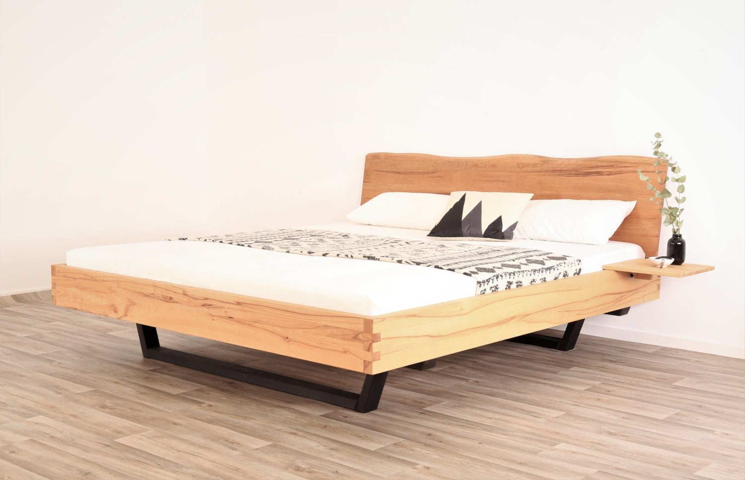 Schräge Frontalansicht von Bett Cofan mit Kufe aus schwarz gebeizter/geölter Buche und Baumkanten-Lehne