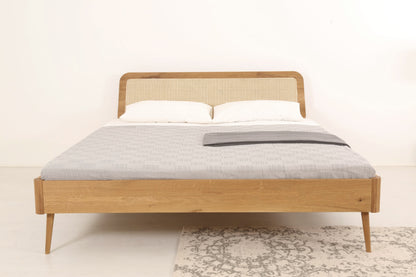 Frontalansicht von Bett Prina mit filigranen, kegelförmigen Füßen und Wiener-Geflecht-Lehne
