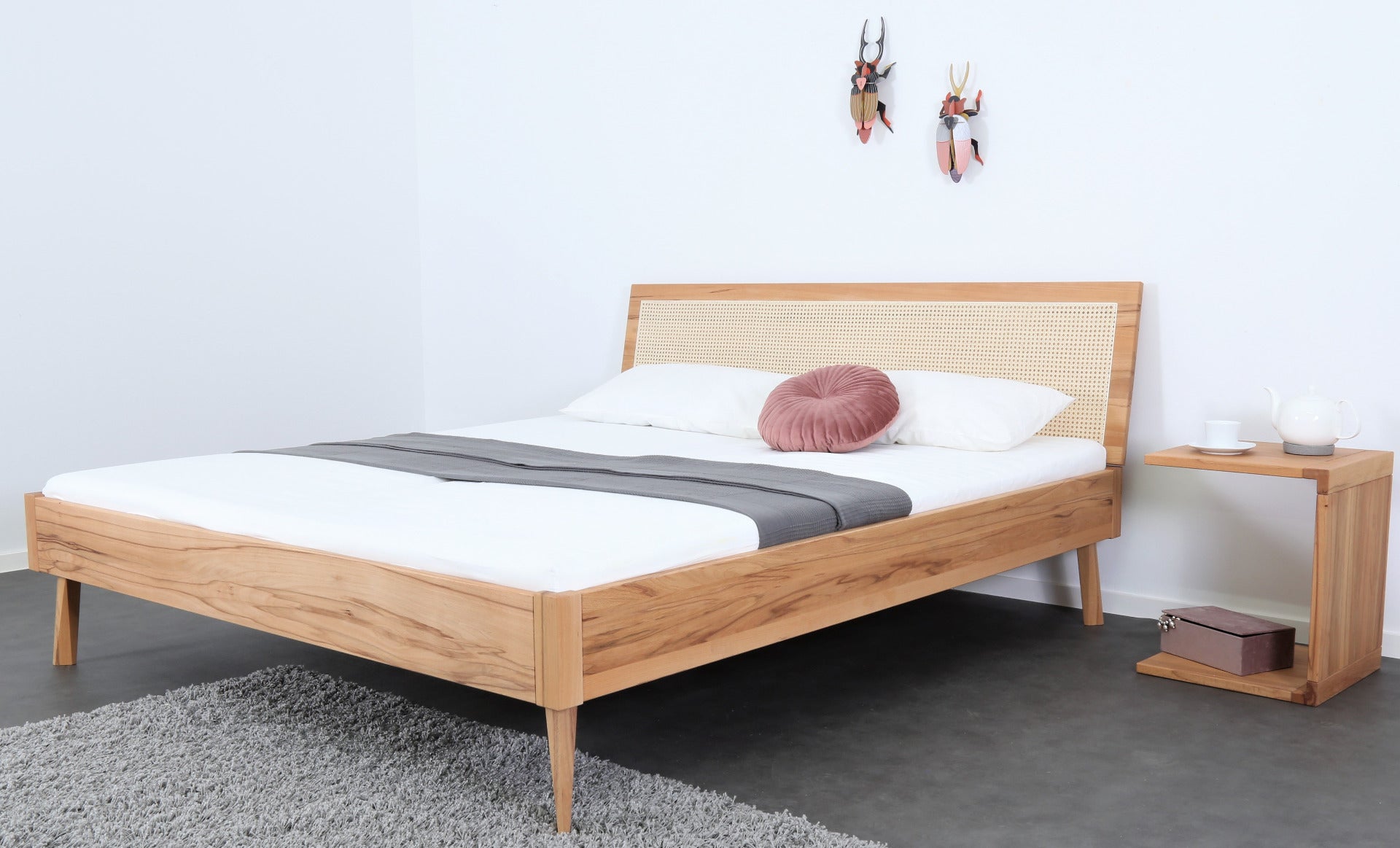 Schräge Frontalansicht von Bett Tuxa Vienna mit Wiener Geflecht Rückenlehne und filigranen Holzfüßen 