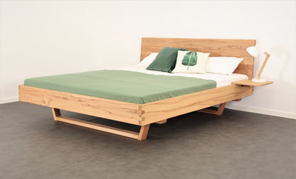 Schräge Frontalansicht von Bett Xeta 01 mit schlichter rechteckiger Rückenlehne und Holzkufen