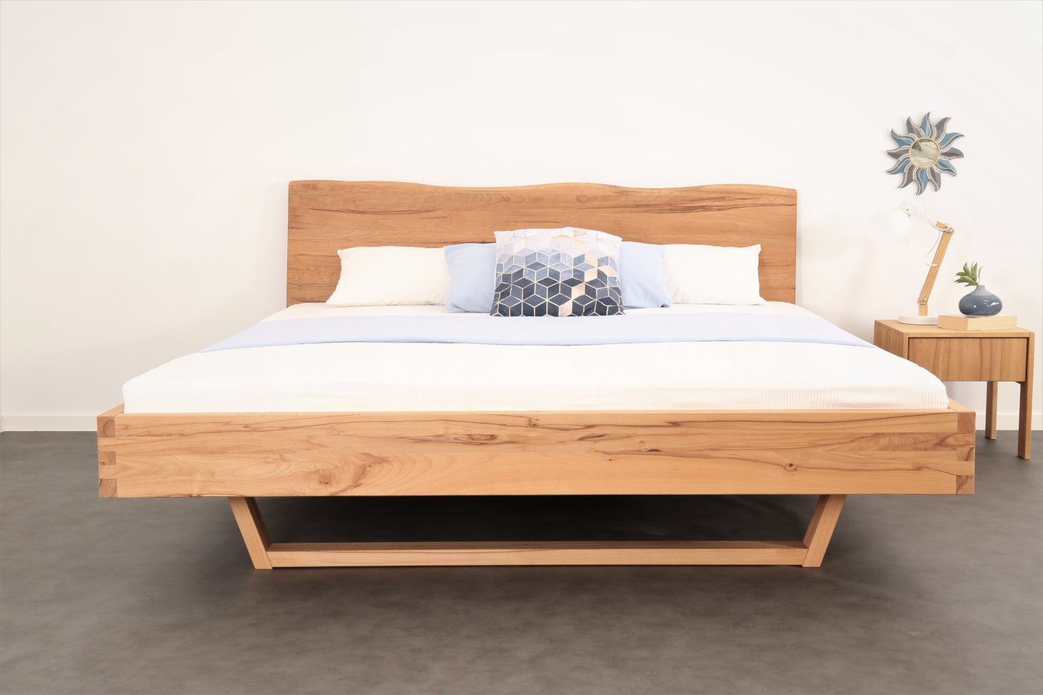 Frontalansicht von Bett Cofan mit Holzkufe und Baumkanten-Lehne.