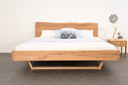 Frontalansicht von Bett Cofan mit Holzkufe und Baumkanten-Lehne.